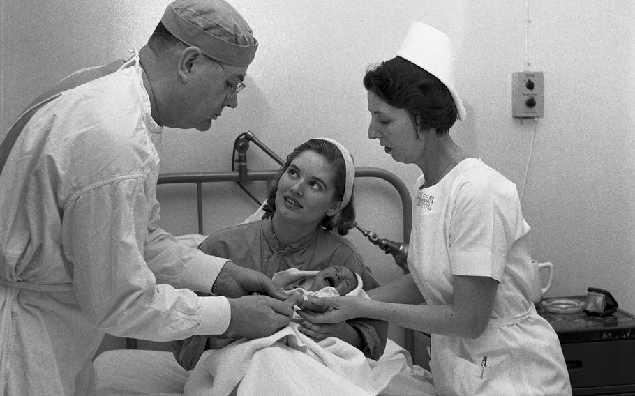 Col. Harold E. Harrison and Chief Nurse Maj. Ruth Steenburgh visit with a new mother and her baby at the 97th U.S. Army Hospital in Frankfurt, Germany.