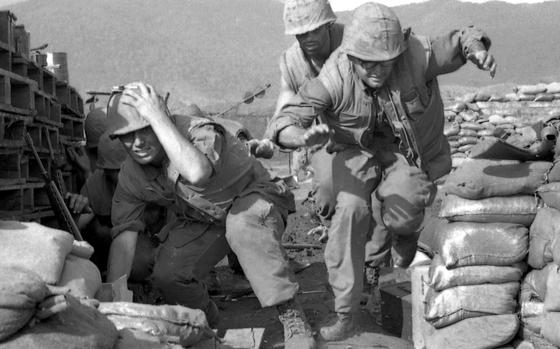 Marines run for cover as North Vietnamese mortar and artillery fire comes down on Khe Sanh base.[cg]; [PUBLISHED CAPTION: While mortar and artillery shells explode around them, U.S. Marines scramble for safety in a bunker at Khe Sanh base in Vietnam, not far from where 151 Reds were killed in a battle Saturday. 01/30/1968]