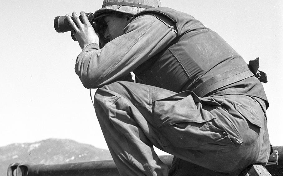 Pvt. Oliver F. Wise of Ironton, Ohio, a member of the 245th Tank Battalion, scans enemy terrain with binoculars before his tank opens fire on North Korean bunkers opposite Sandbag Castle in April, 1953. 