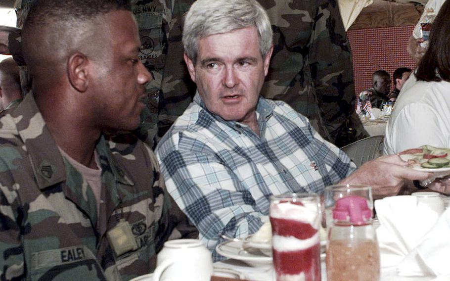 Staff Sgt. Lynwood Ealey (left sitting) eats lunch with then-Congressman Newt Gingrich at the dining facility at Camp McGovern, May 31, 1998.