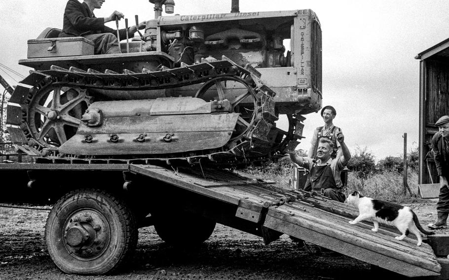  A farm cat takes its chances against a tractor being unloaded at Kiln Farm, where American-made machinery was a common sight during the postwar years. “If a piece breaks off a D-2 Caterpillar or an Allis-Chalmers tractor, you can weld it back together and it sticks like a couple of pieces of flypaper,” said the farm’s manager. “You can’t do that with some of our British machines. Difference is in the temper of the steel, I guess.”