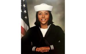 Angelina Resendiz poses in her Navy uniform with an American flag behind her right shoulder.