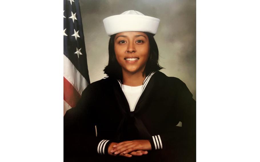 Angelina Resendiz poses in her Navy uniform with an American flag behind her right shoulder.