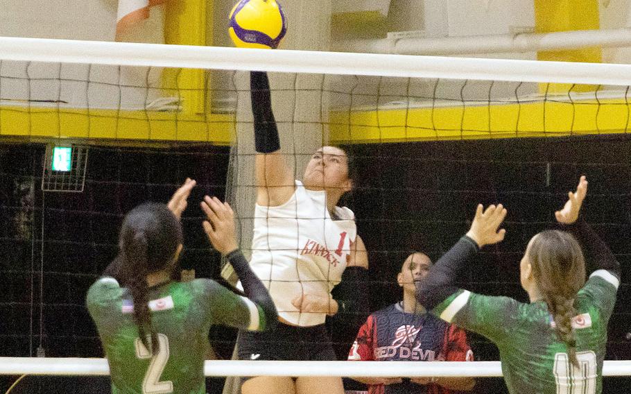 Nile C. Kinnick's Leona Turner spikes between Kubasaki's Runa Holladay and Jackie Mitchell.