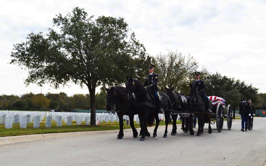 Soldiers participate in a funeral procession with a horse-drawn carriage.