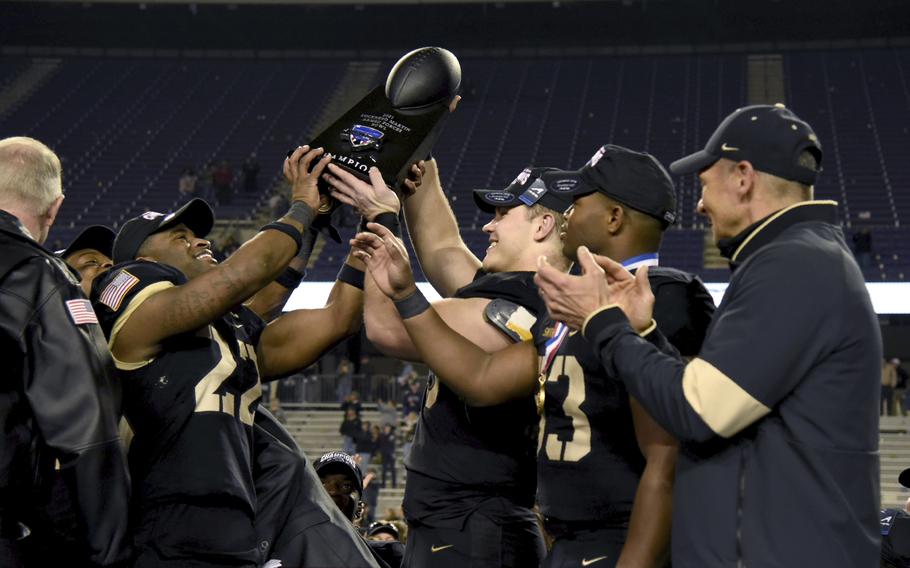 Army head coach Jeff Monken, right, looks on as his team celebrate with the trophy after their win in the Armed Forces Bowl NCAA college football game against Missouri in Fort Worth, Texas, Wednesday, Dec. 22, 2021. 