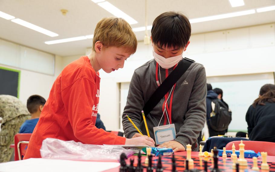 Ethan Meskimen, a fourth-grader at Shirley Lanham Elementary School, helps Tatsuaki Watanabe fill out a chart during a chess tournament at Naval Air Facility Atsugi, Japan, Feb. 23, 2024.