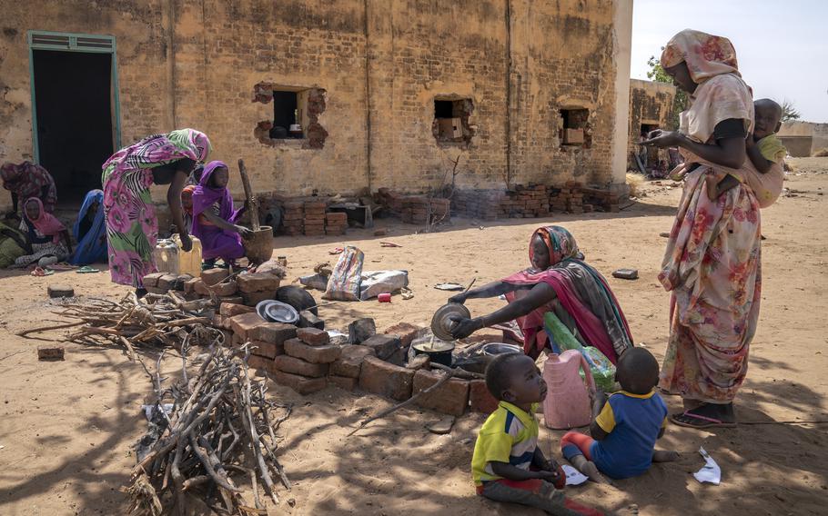 Women prepare a meager meal in the yard of a former primary school in Sirba, a town about 15 miles north of El Geneina, the capital of West Darfur. The yard is one of numerous sites where thousands displaced by the war are staying.
