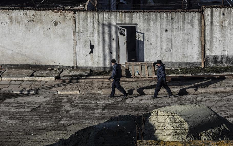 Prisoners carry a wooden crate to transport dirt outside at a Ukrainian detention camp.