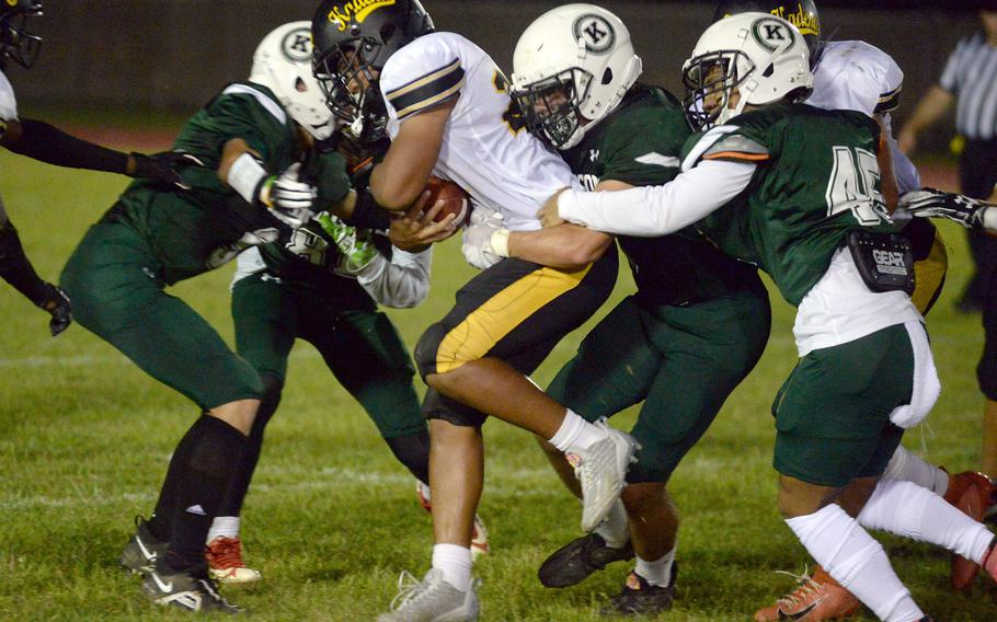 Kadena running back Jeremiah Drummer gets wrapped up by several Kubasaki defenders.