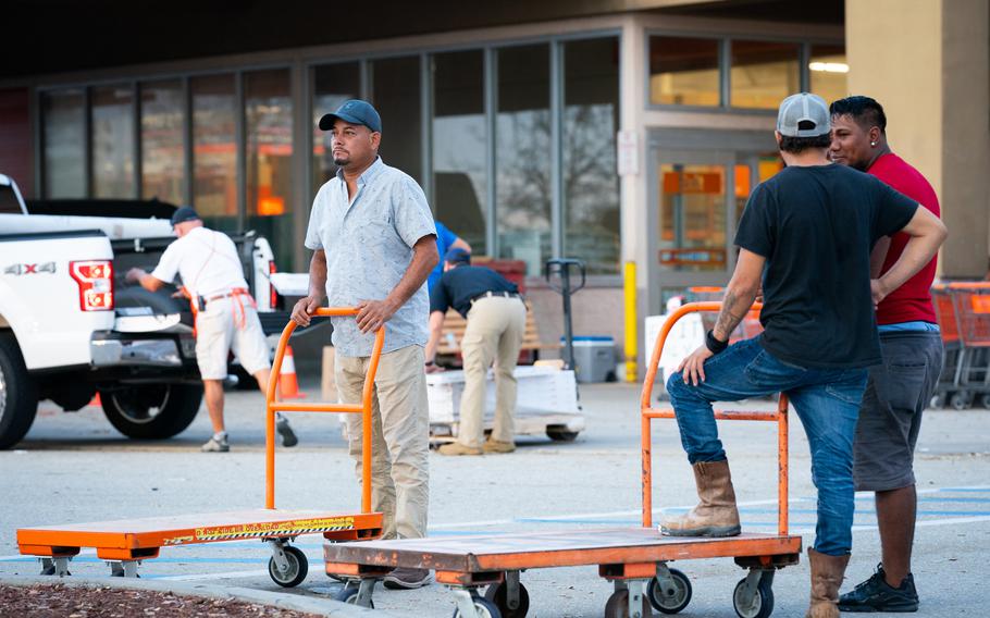 Fernando Jimenez, 46, left, is originally from Honduras, but has lived in the United States since the mid 1980s and has legal residency. He traveled from Austin, Texas, to Florida for work with his two friends, Heber, 32, and Bryan, 24, right. They spent some nights sleeping in a tent in the Home Depot parking lot as they looked for work. 