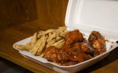 Fried chicken wings are packaged with battered fries in a delivery carton from Ishan's Gourmet Hot Wings in Kaiserslautern.