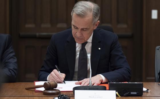 Prime Minister Mark Carney signs a document during cabinet meeting on Parliament Hill, Friday, March 14, 2025 in Ottawa. (Adrian Wyld/The Canadian Press via AP)