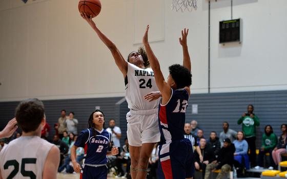 Naples’ Cameron Collins goes to the hoop against Aviano’s Malakai Harkley  in a Division II semifinal at the DODEA-Europe basketball championships in Ramstein, Germany, Feb. 17, 2023. Naples beat Aviano 68-49 to advance to Saturday’’s final against AOSR.