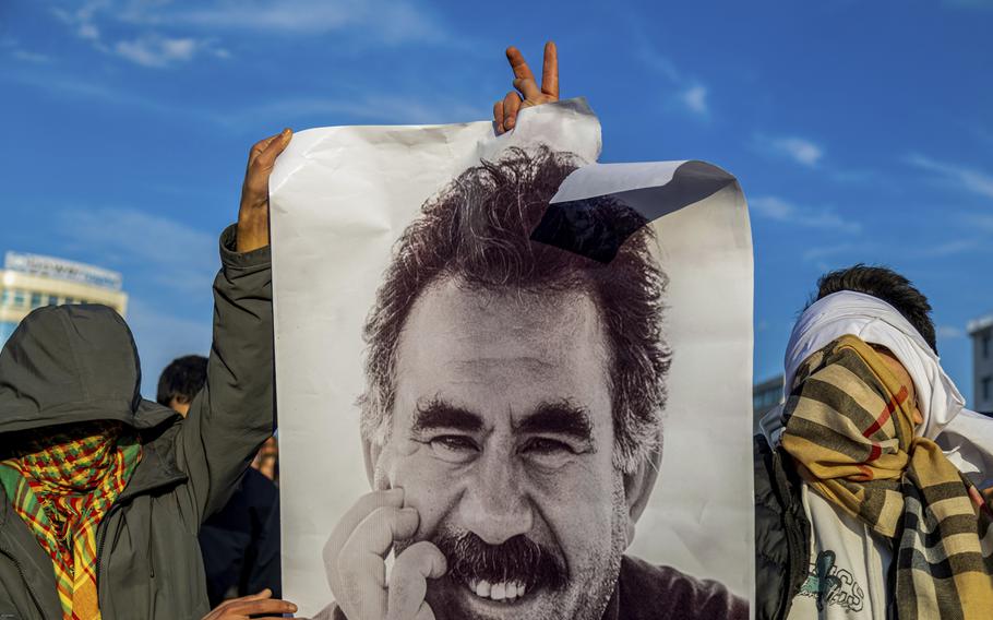 Masked young people hold up a large photo.