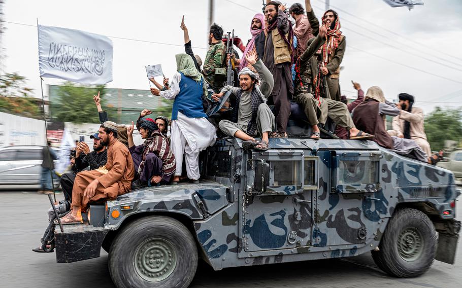 Taliban fighters hold weapons as they ride on a Humvee to celebrate their victory day near the U.S. embassy in Kabul, Afghanistan, on Monday, Aug. 15, 2022. 