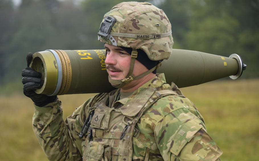 A soldier carries an artillery shell over his shoulder.