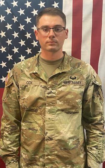 A vertical photo of a soldier in uniform against an American flag.