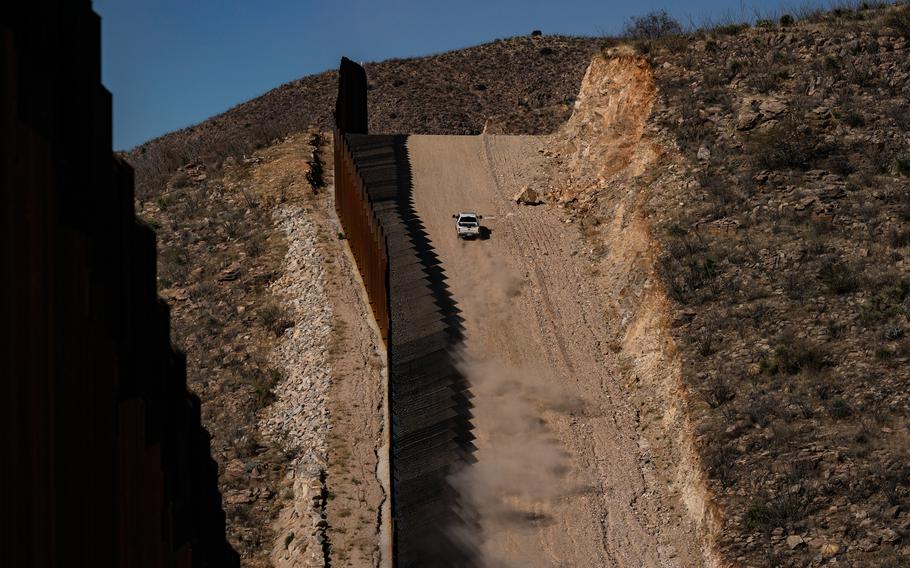 A U.S. Border Patrol vehicle travels along the U.S.-Mexico border wall near Sasabe, Ariz., on Jan. 23, 2022. 