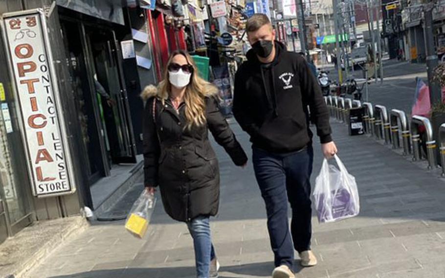 People wear masks after shopping outside Osan Air Base, South Korea, Friday, Feb. 11, 2022.