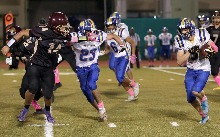 Yokota's Caleb Jones skirts left end with an escort from teammate Owen Taylor as Matthew C. Perry's Roy Clayton looks to slow him down.