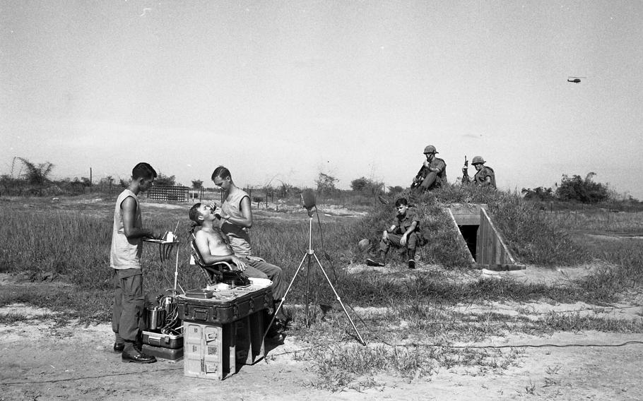 Capt. Earle Yeamans examines an infantryman’s teeth as his fellow soldiers look on. 