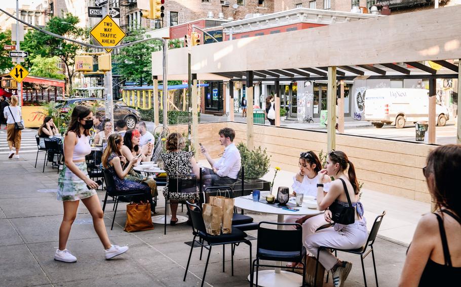 Pedestrians sit in the outdoor dining section of a restaurant in the SoHo neighborhood of New York on May 19, 2021. 