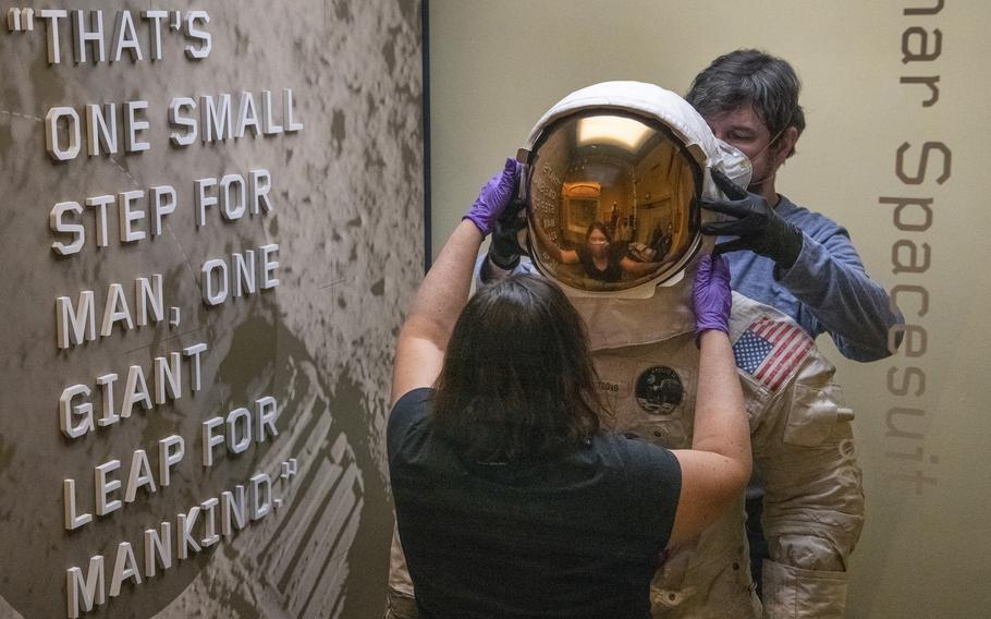 Lisa Young removes the helmet of the Armstrong Apollo 11 A7-L pressure suit with the help of Chris Crandall as the suit is temporarily stored.
