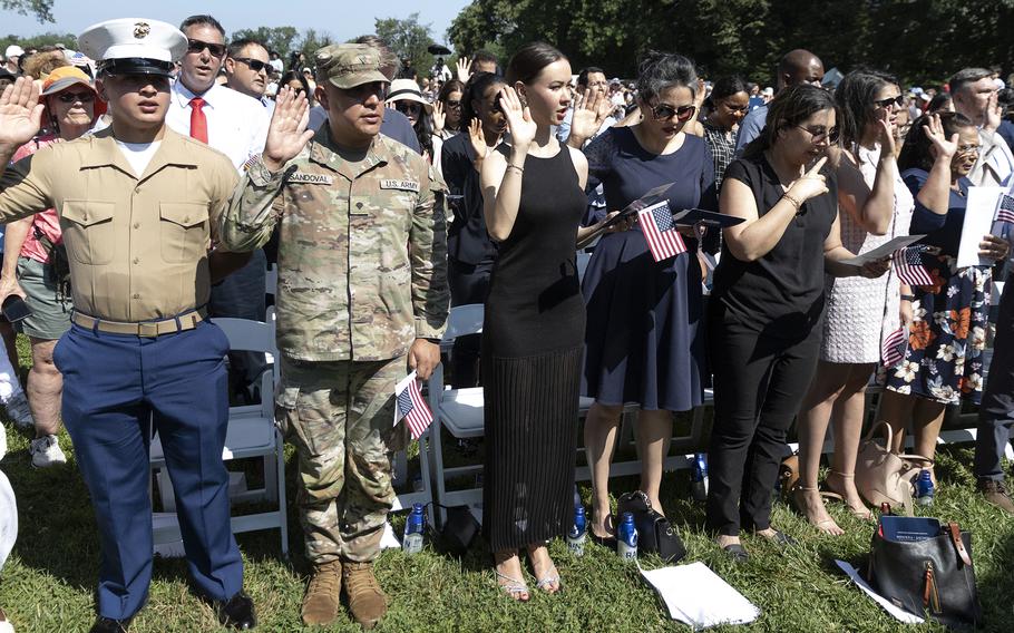 US service members from the Army and the Marine Corps and other individuals taking the Oath of Allegiance during a naturalization ceremony.