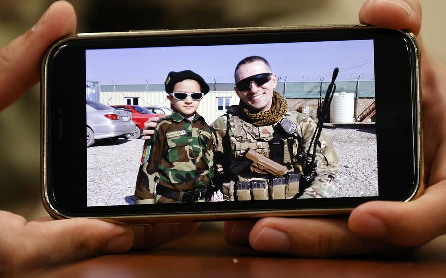 United States Space Force Lt. Co. Adam Howland displays a photo on his cell phone, taken in 2015, of him and a boy in Afghanistan.