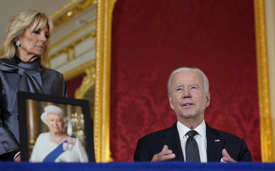 President Joe Biden signs a book of condolence at Lancaster House in London, following the death of Queen Elizabeth II, Sunday, Sept. 18, 2022, as first lady Jill Biden looks on.