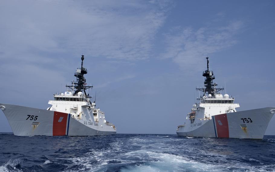 Two Coast Guard ships cruising side by side.