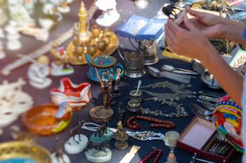 At a vibrant market, hands sift through an array of exquisite vintage treasures.