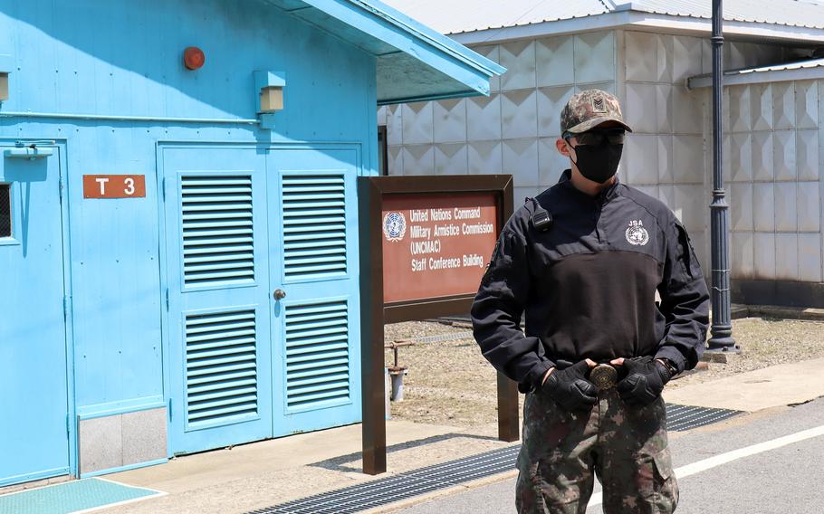 A South Korean soldier stands guard in front of a blue building at the DMZ.