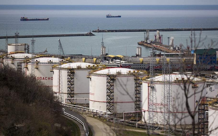 Oil storage tanks stand at the RN-Tuapsinsky refinery, operated by Rosneft Oil Co., as tankers sail beyond in Tuapse, Russia, on Monday, March 23, 2020.