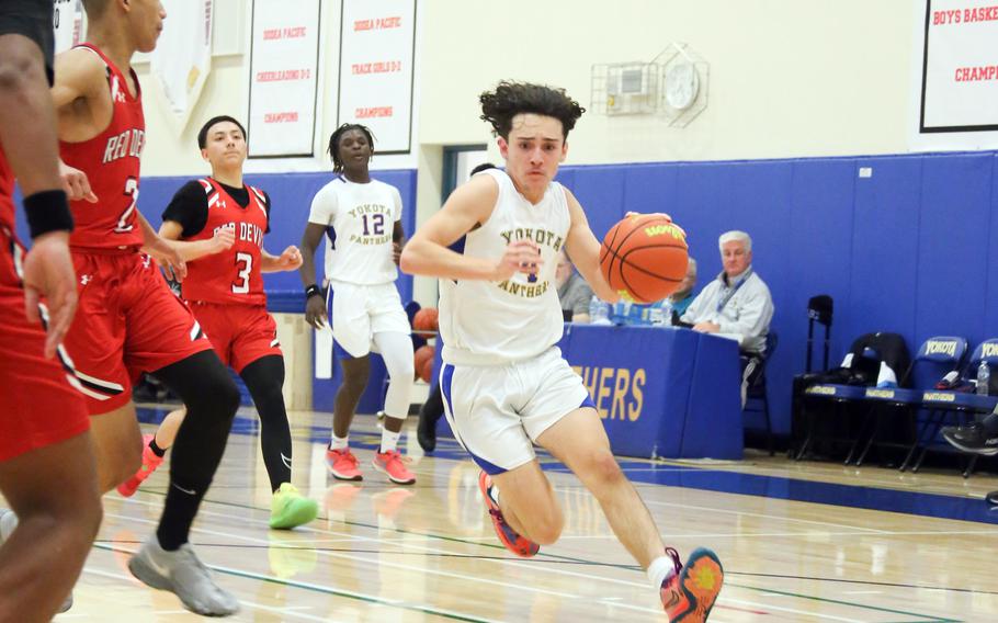 Yokota's Rodrigo Negron drives against Nile C. Kinnick defenders during Tuesday's DODEA-Japan/Kanto Plain boys basketball game. The Red Devils won 73-61.