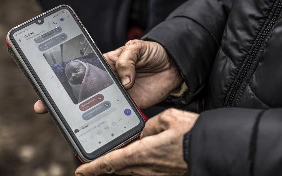 Maria Kamianetska, shown on Nov. 25, 2022, in Novosolone, Ukraine, holds a phone showing a photo of her newborn son, Serhii, that she sent to Vitalii Podlianov, the boy's father, after he was born on Nov. 21. Serhii was killed when a missile hit a hospital in Vilnyansk on Nov. 23.