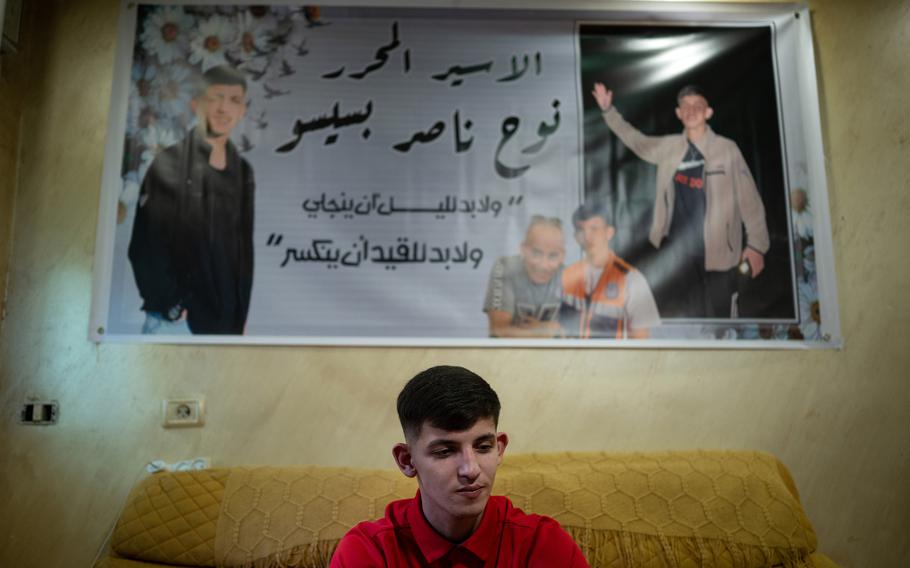 Noah Bseso sits under a banner with his image in the living room of his home.