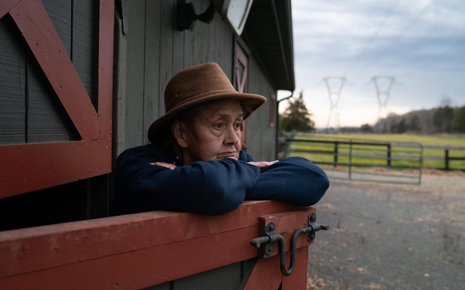 Page Snyder, owner of Pageland Farm, stands at the entrance of an unused horse barn in December. The power lines in the background are one reason she and her neighbors are now trying to convert their land into a 2,100-acre data center complex, sparking outrage from the broader community in a rural swath of Prince William County.