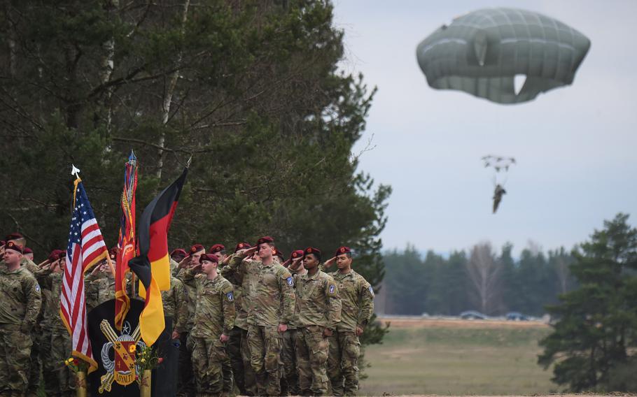 Members of the 319th Airborne Field Artillery Regiment salute in formation while paratroopers complete their jump during the opening moments of the drop zone renaming ceremony in honor of Cpl. Emmanuel Hernandez at Grafenwoehr, Germany, on April 20, 2023.