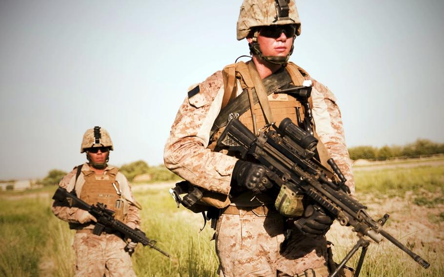 Lance Cpl. Karl Schmidt, left, and Pfc. Aramis Sandoval of 3rd Marine Regiment patrol through farmland in this undated photo taken in Afghanistan.