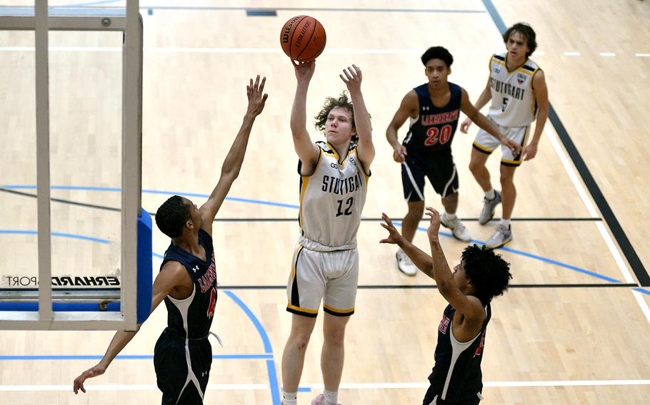 Stuttgart senior Chris Hess shoots as Lakenheath junior Jayden Sheperd, left, and senior Dante Thompson defend during pool-play action of the DODEA European basketball championships on Feb. 14, 2024, at the Wiesbaden Sports and Fitness Center on Clay Kaserne in Wiesbaden, Germany.