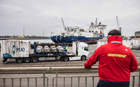 A Greenpeace activist observes the unloading of several cylinders of uranium from Russia at the port of Dunkirk, France, on March 20, 2023.