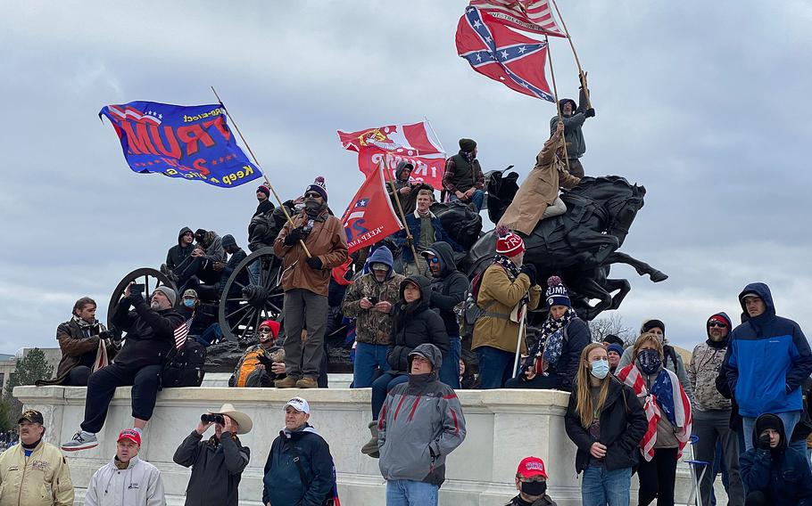 Trump supporters, including one waving a Confederate flag, watch rioters storm the Capitol in Washington, D.C., on Jan. 6, 2021. 

Robert Reid/Stars and Stripes