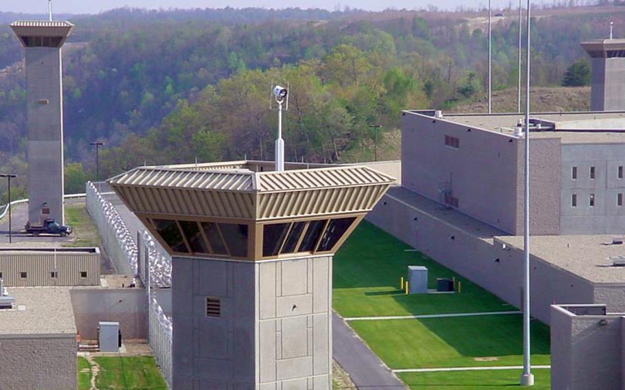 Prison watchtowers overlooking a beige building and lawn.