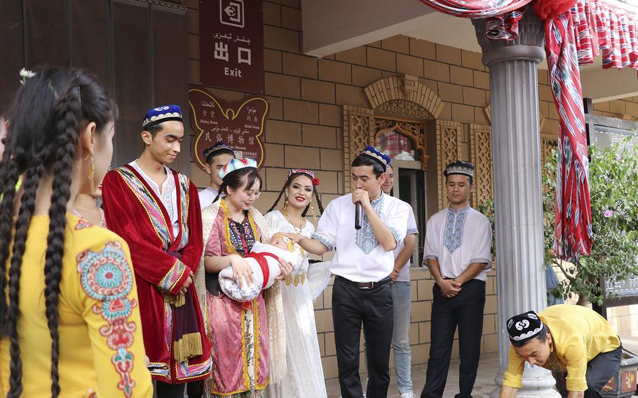 A Chinese tourist holds a baby doll at the end of an imitation wedding performance for tourists in Kashgar on Aug. 3, 2022.