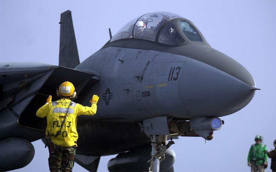 A plane director on the USS Kitty Hawk’s flight deck directs an F-14 Tomcat from VF-154 shortly after the aircraft landed Monday, April 15, 2002.