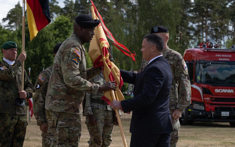 Col. Kevin A. Poole, incoming commander of U.S. Army Garrison Bavaria, receives the guidon from the diirector of Installation Management Command Europe, Tommy R. Mize, during a ceremony at Tower Barracks in Grafenwoehr, Germany, July 12, 2022.