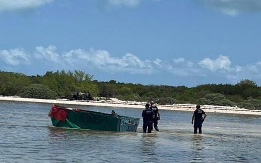 Federal agents stand near a boat in shallow water off a remote island about 20 miles west of Key West, Florida, where 12 migrants from Cuba were found stranded on June 13, 2022. 