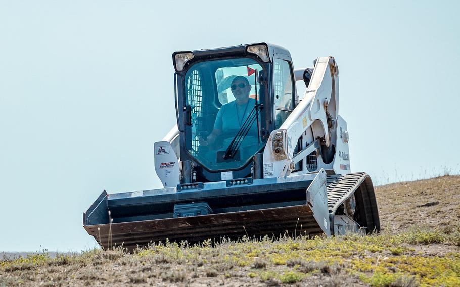 A U.S. military employee uses a Bobcat skid steer.